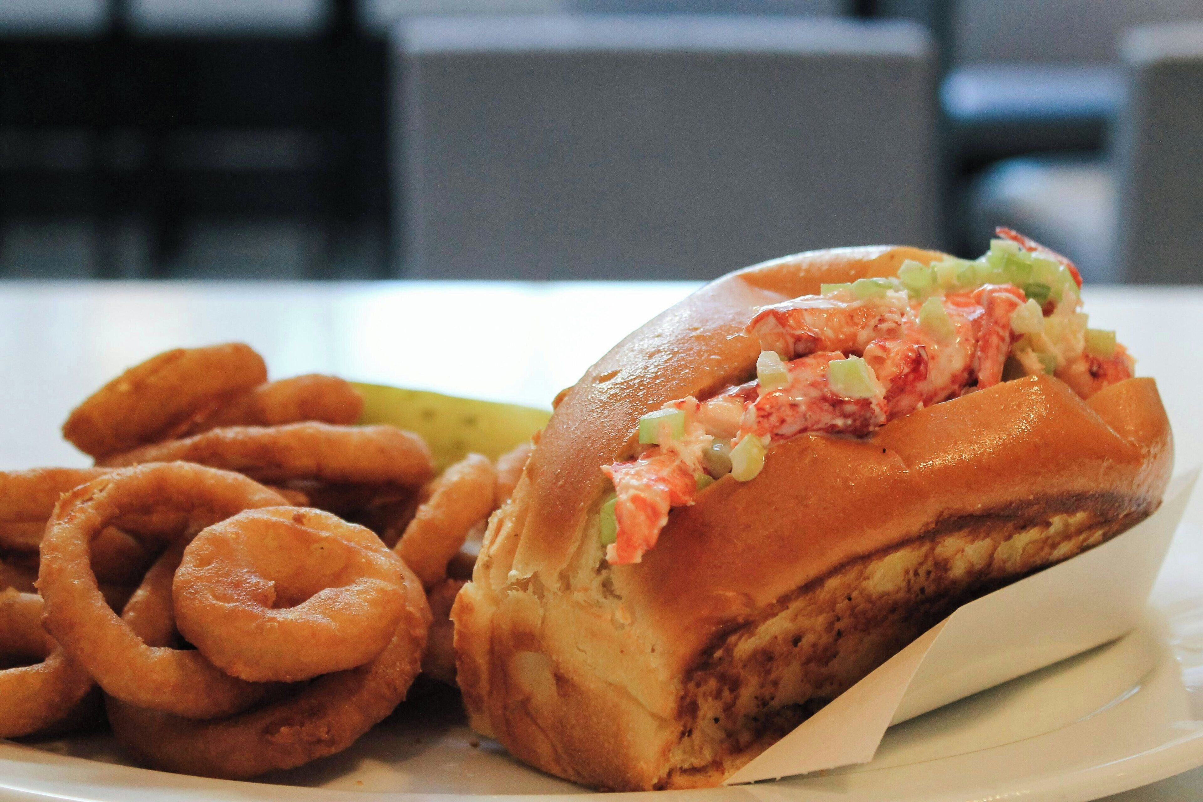 A sandwich with a side of onion rings on a white plate.