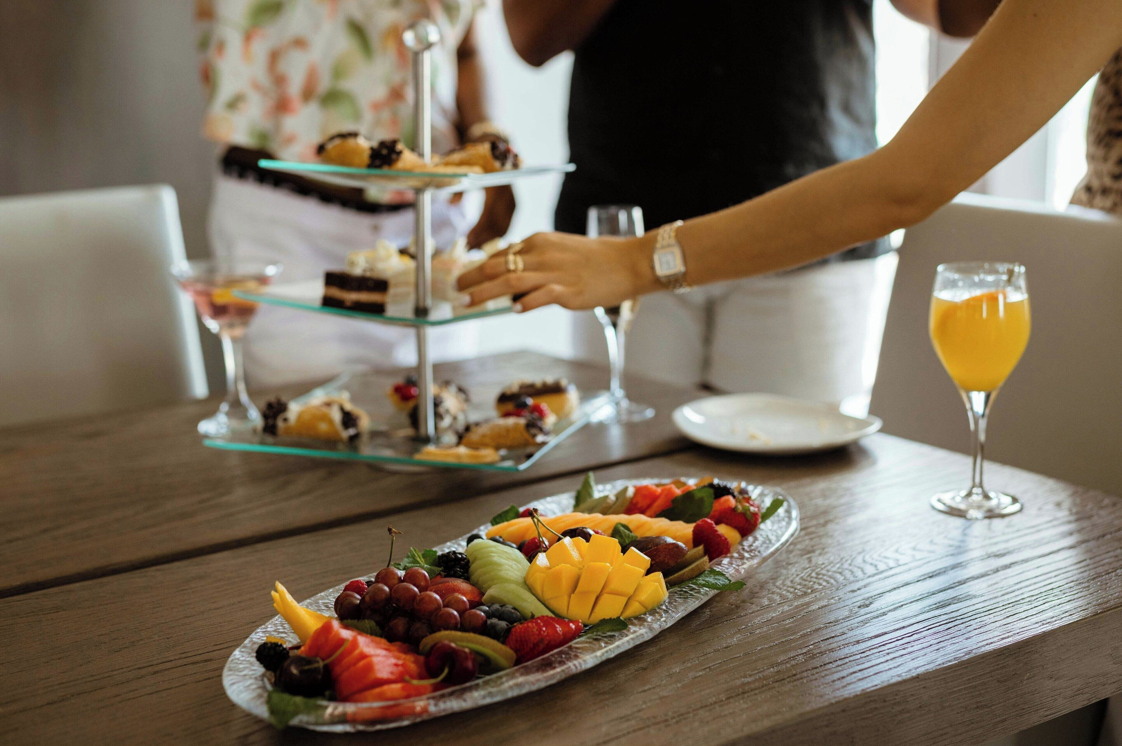 Une table en bois avec une assiette de fruits et un verre de jus d’orange.
