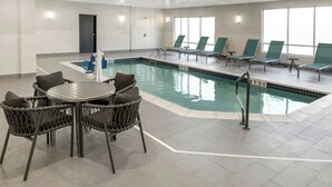Une piscine intérieure avec un espace détente, des fauteuils et une table.