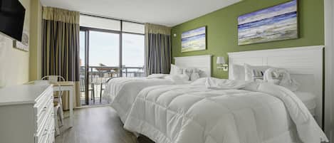 A hotel room with a large bed, a desk, and a balcony with a view.