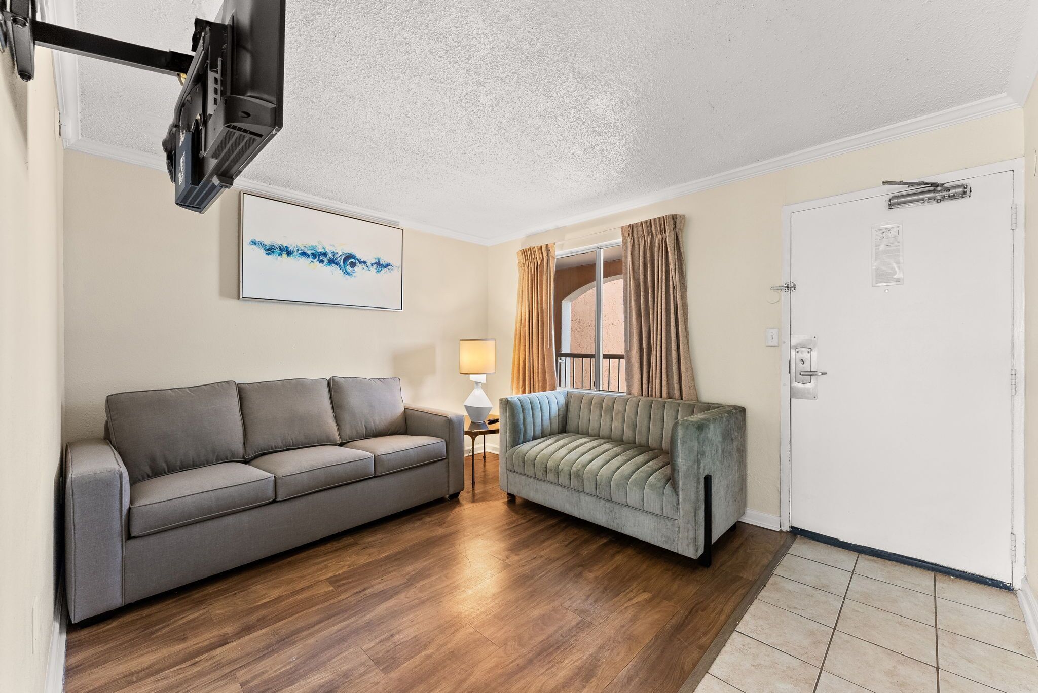 A living room with a grey sofa, a light grey sofa, a lamp, and a door with a window.