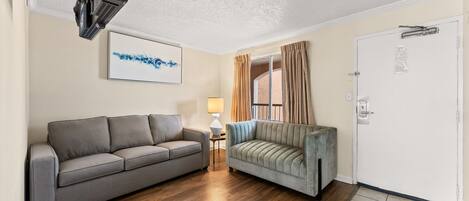 A living room with a grey sofa, a light grey sofa, a lamp, and a door with a window.