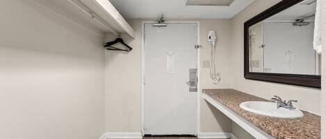 Un baño con una puerta blanca, un lavabo con encimera de granito y un espejo con marco oscuro.