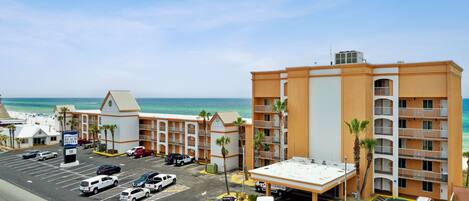 A hotel with multiple floors, a parking lot, and a view of the ocean.