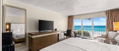 Una habitación de hotel con una cama grande, televisión, escritorio y vista al océano.