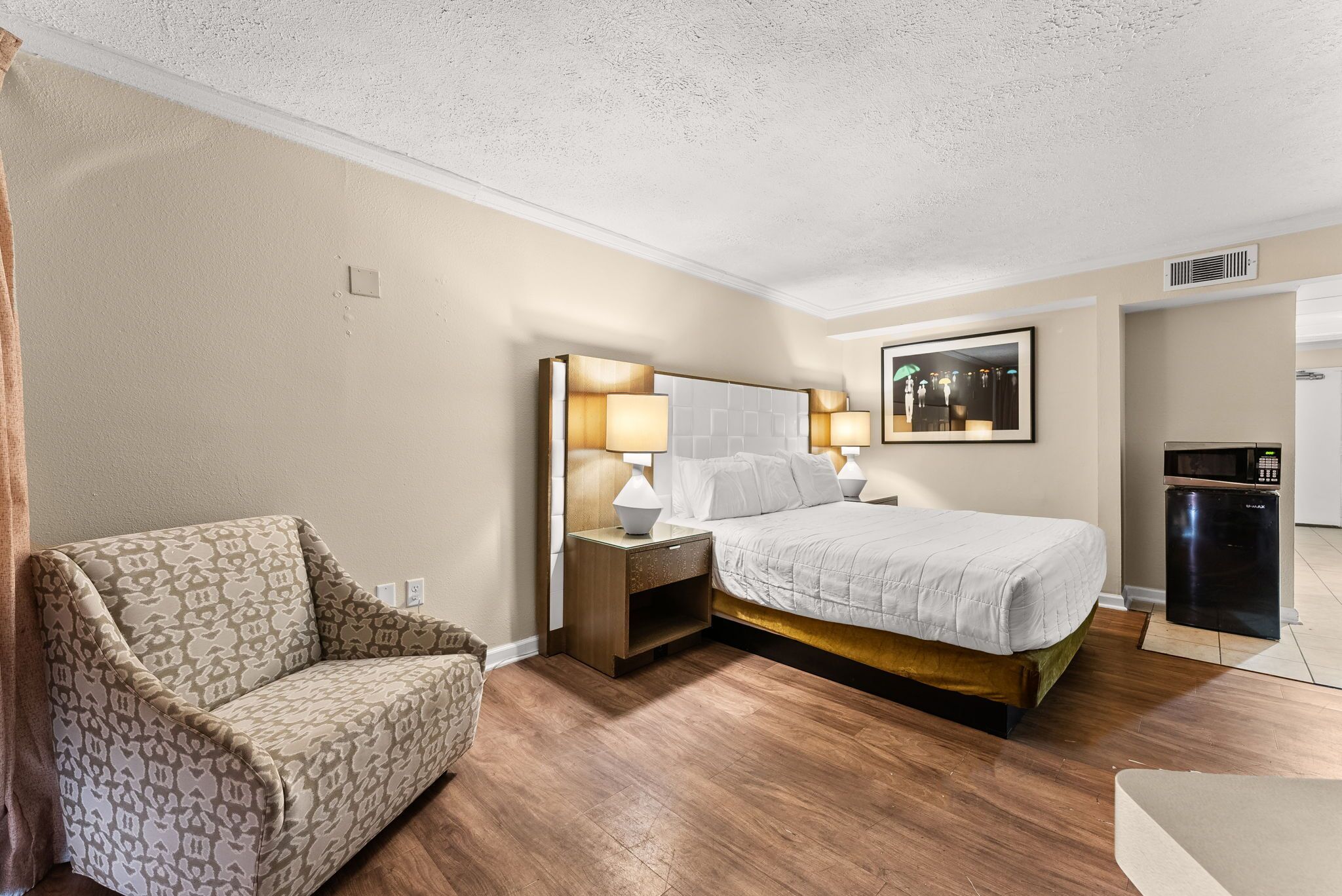 Een hotelkamer met een bed, nachtkastjes, een lamp, een stoel en een magnetron.