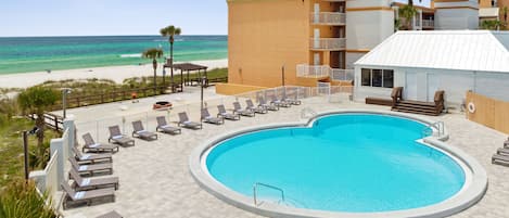 Zona de piscina con sillones de descanso y vista a la playa.