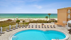 A swimming pool with lounge chairs and a view of the beach. - Seahaven Beach Hotel (Panama City Beach)