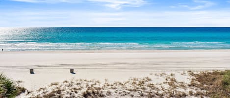 Una playa con cielo despejado, mar tranquilo y orilla de arena.