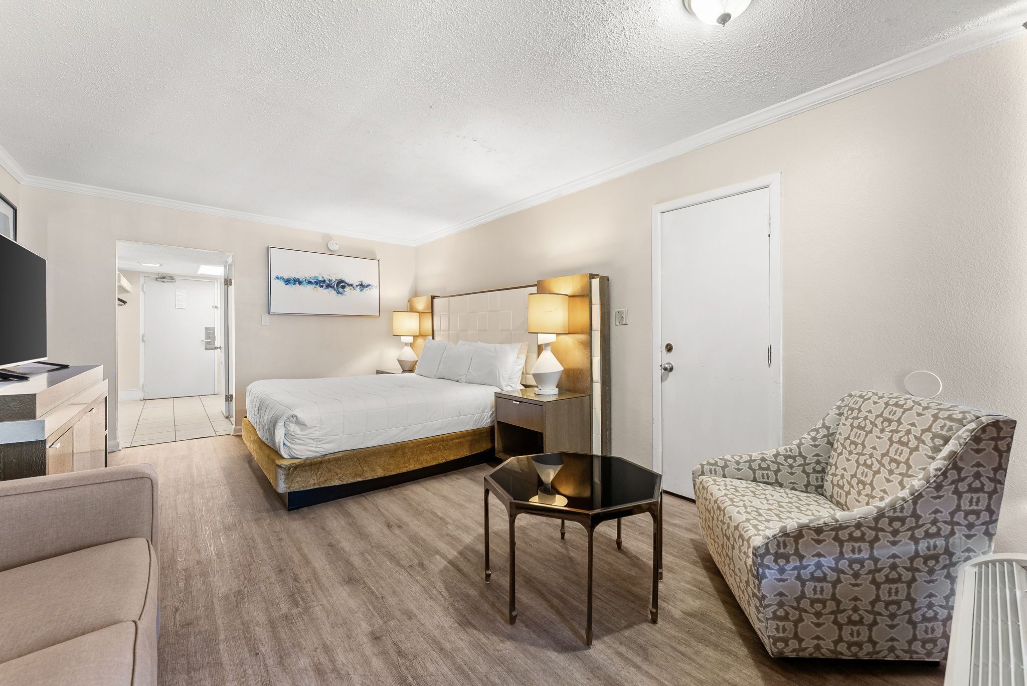 Une chambre d’hôtel comprenant un lit, une table de chevet, une lampe, une chaise et une petite table.