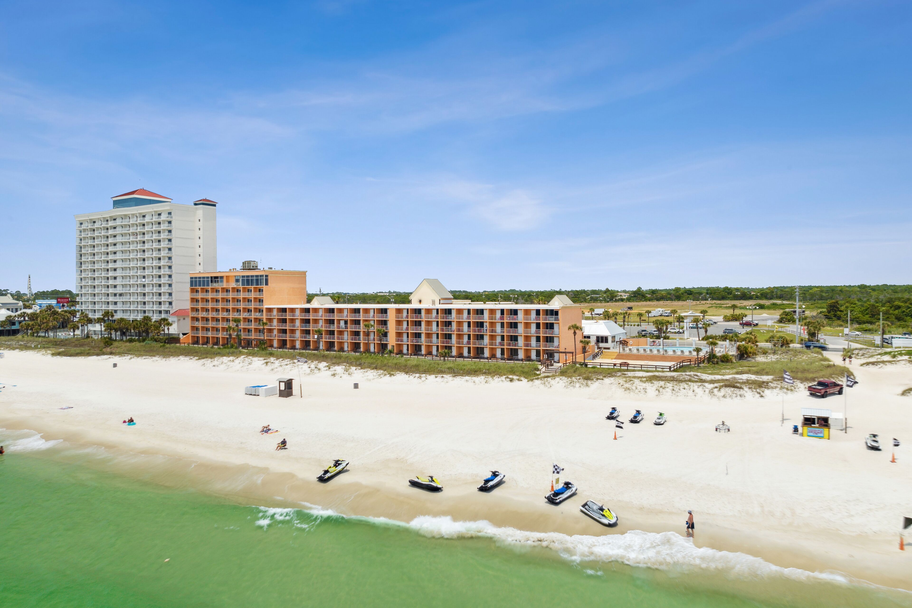 A beachfront hotel with multiple buildings, a sandy beach, and several boats.