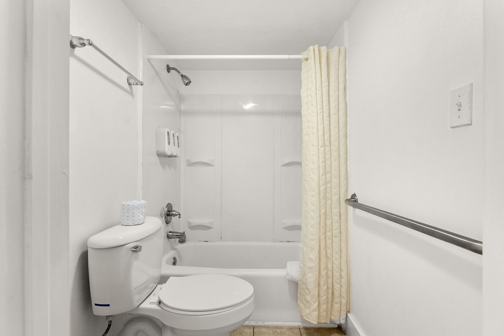 A small, white bathroom with a toilet, shower, and bathtub.