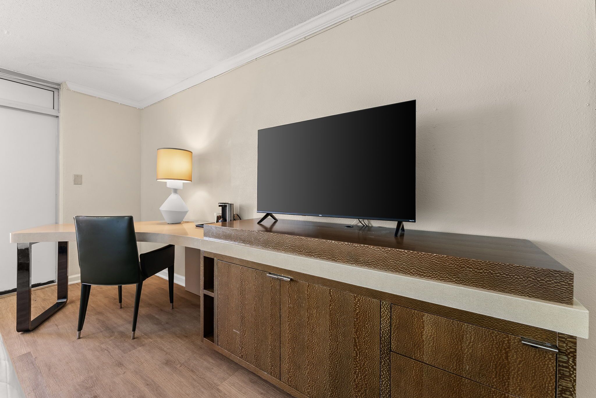 Eine moderne Küche mit Flachbildfernseher an der Wand, einem Esstisch mit Stühlen und Holzschränken.