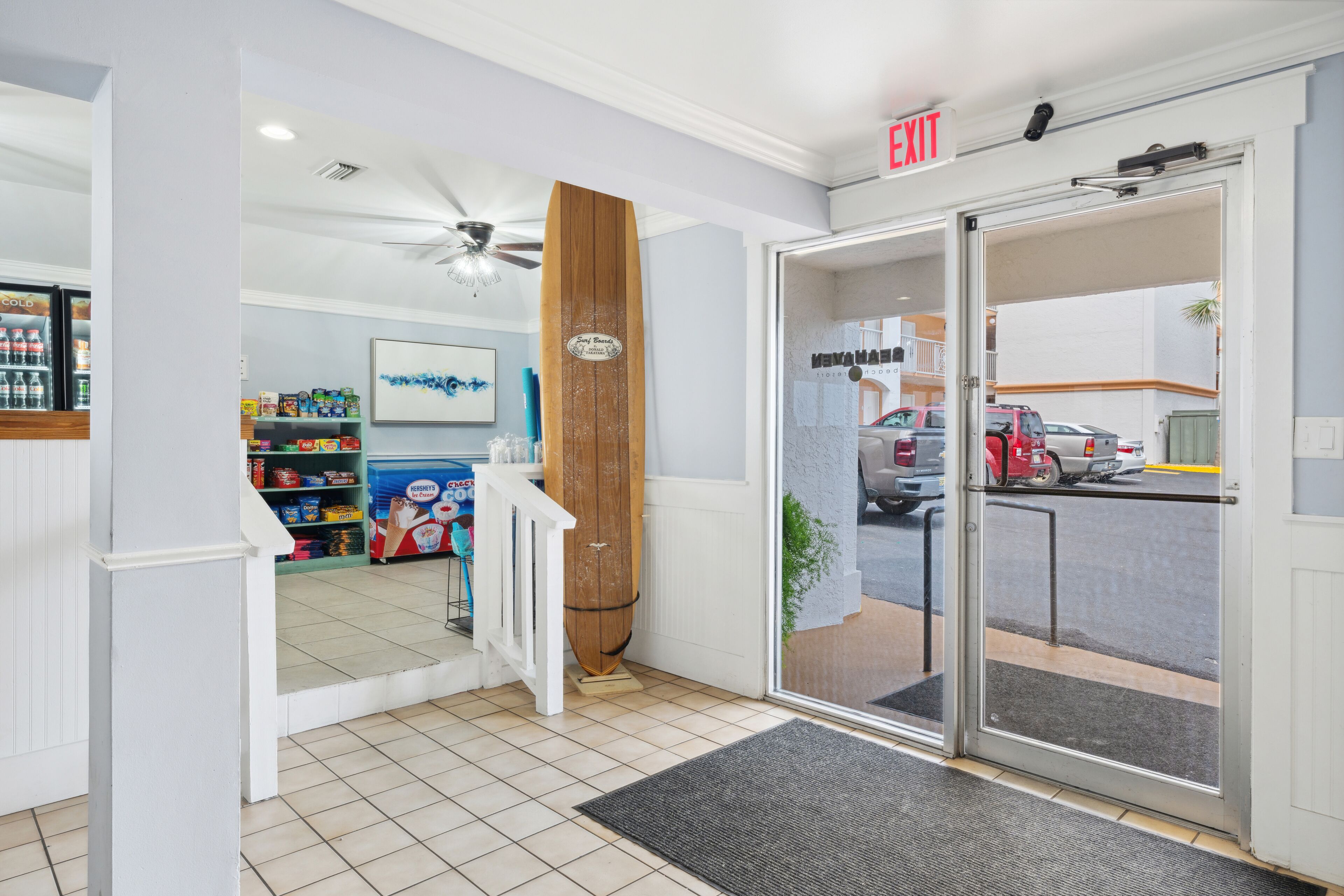 L’entrée d’un hôtel, avec une porte en bois, une porte en verre, un ventilateur de plafond et un sol carrelé.