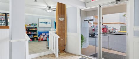 L’entrée d’un hôtel, avec une porte en bois, une porte en verre, un ventilateur de plafond et un sol carrelé.