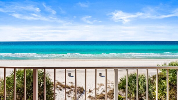 A beach view with a clear sky, a sandy shore, and a railing in the foreground. - Seahaven Beach Hotel (Panama City Beach)