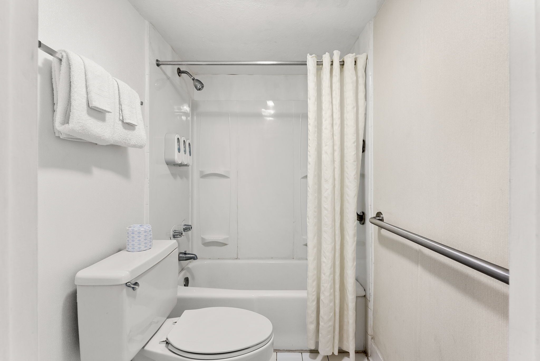 A small, white bathroom with a toilet, a shower, and a bathtub.