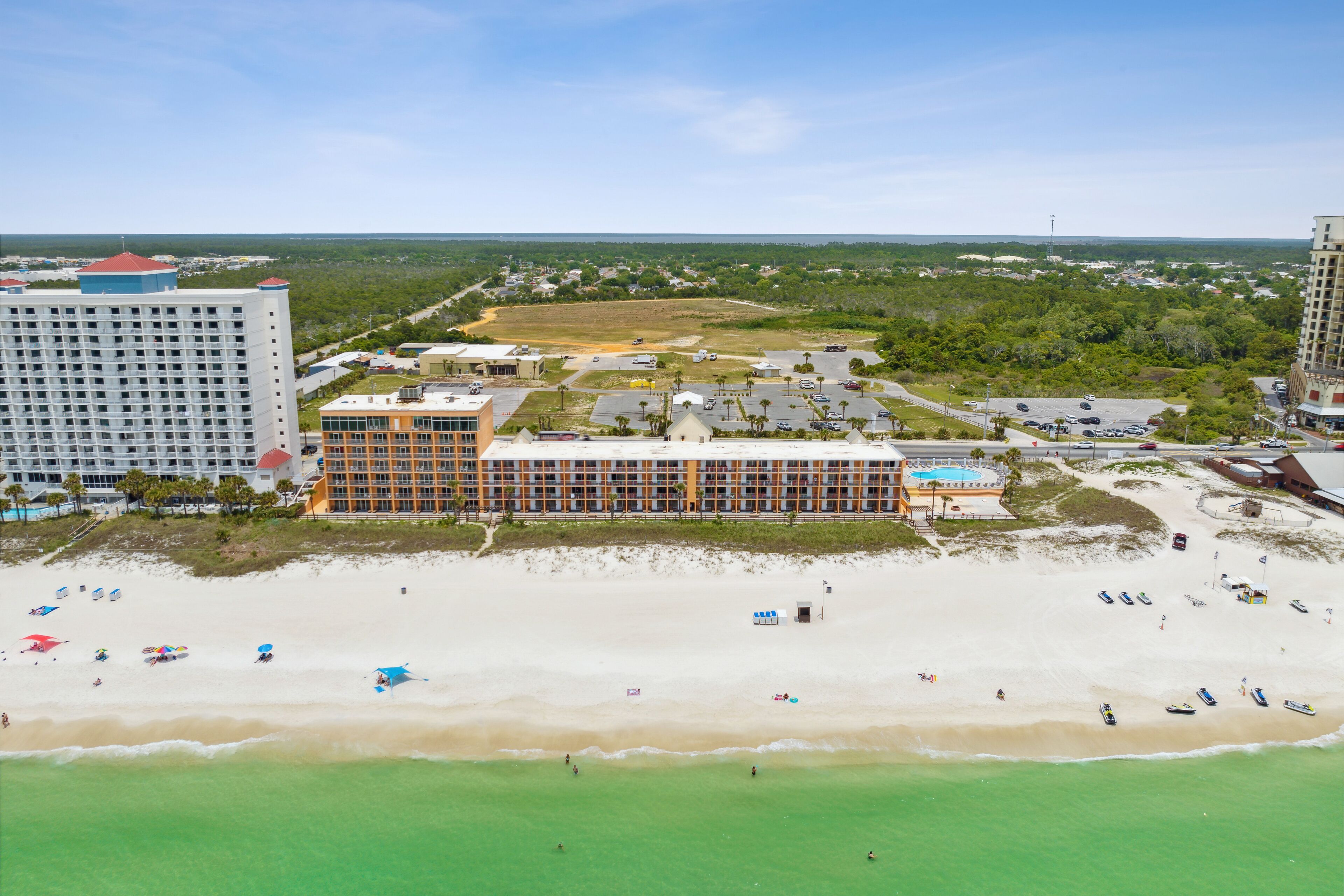 A coastal hotel with multiple buildings, a beach, and a view of the ocean.