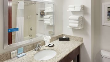 A bathroom with a granite countertop, a sink, a mirror, a towel rack, and a toilet.