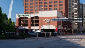A hotel with a prominent arch structure in the background, a sign for Hampton Inn, and a TGI Friday's restaurant. - Hampton Inn St. Louis-Downtown (At the Gateway Arch) (St. Louis)