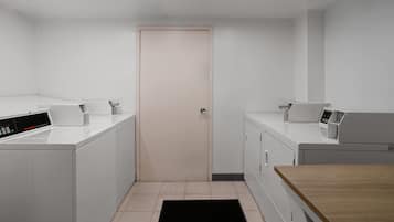 Una sala de lavandería con dos lavadoras, una secadora y una mesa de madera.