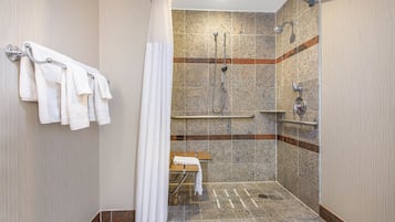 Ein modernes Badezimmer mit Dusche, Handtuchhalter und Sitzbank.