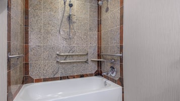 Ein Badezimmer mit Badewanne, Dusche und Haltegriffen.