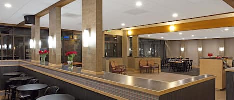 A modern hotel lobby with a bar area, seating arrangements, and a reception desk.