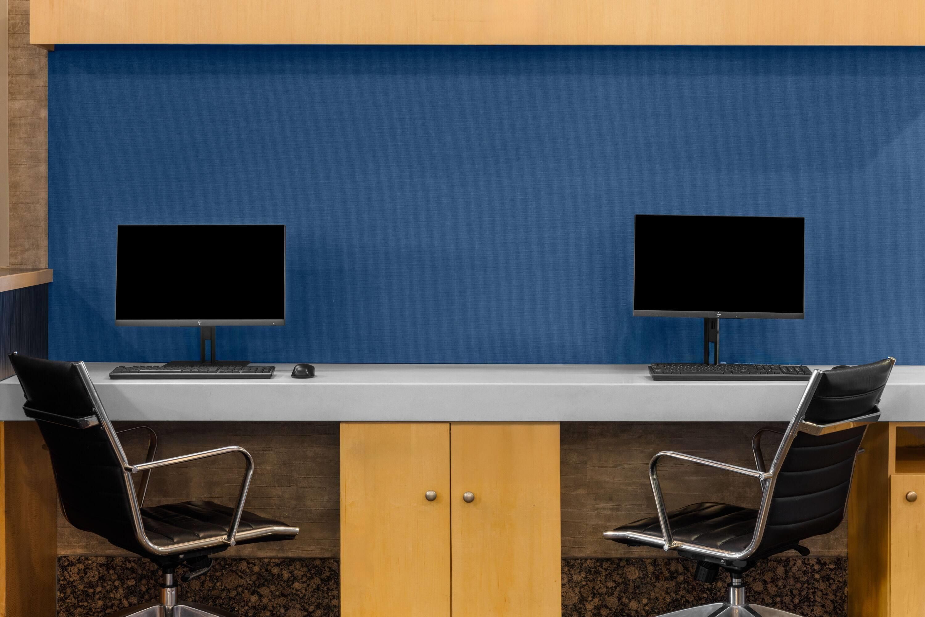 A workspace with two black chairs, a white desk, and two monitors.