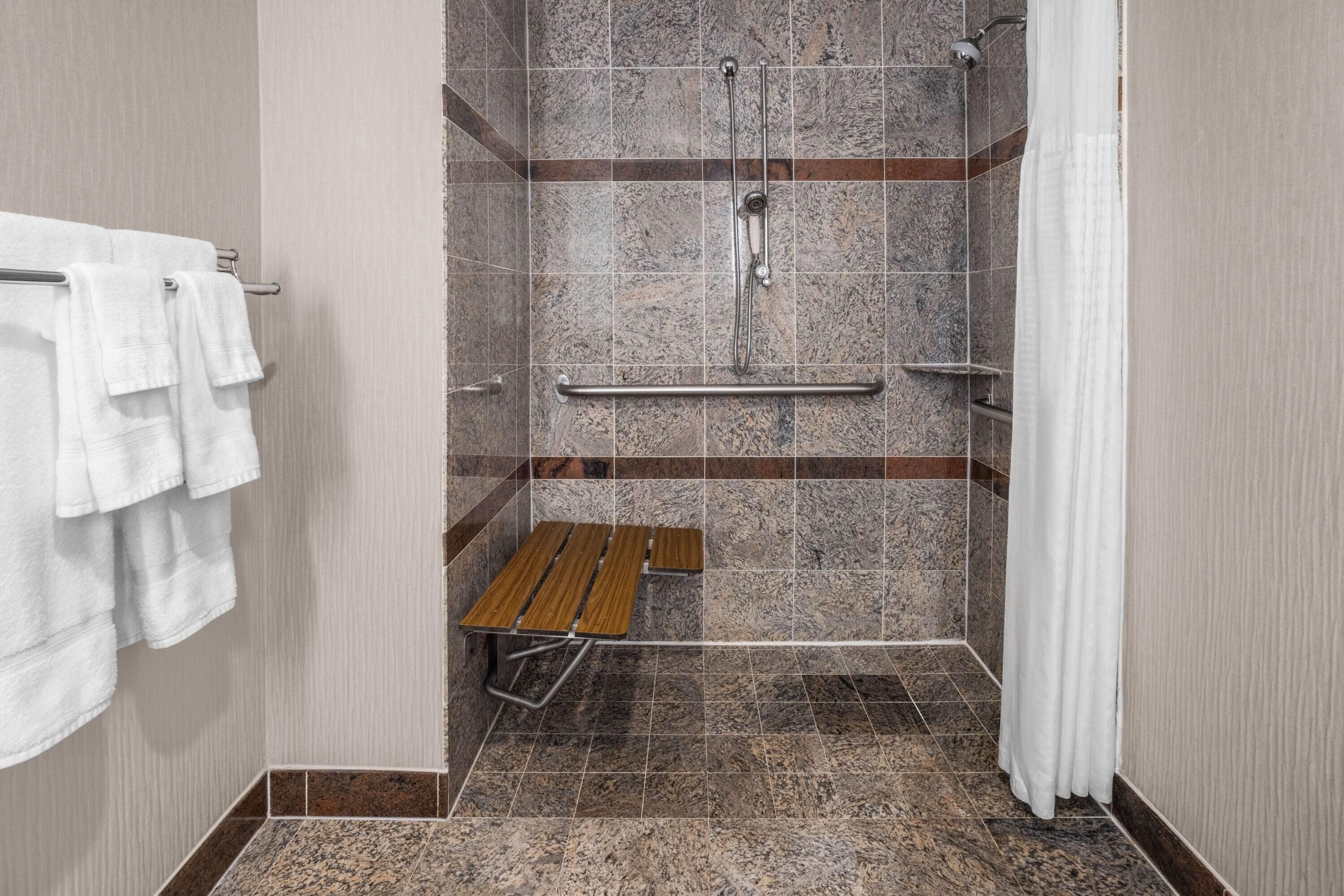 Un espace douche équipé d’un banc, de barres d’appui et d’un porte-serviettes.