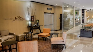 A lobby with a reception desk, seating area, and a staircase. - Hilton Garden Inn Guatemala City (Guatemala City)