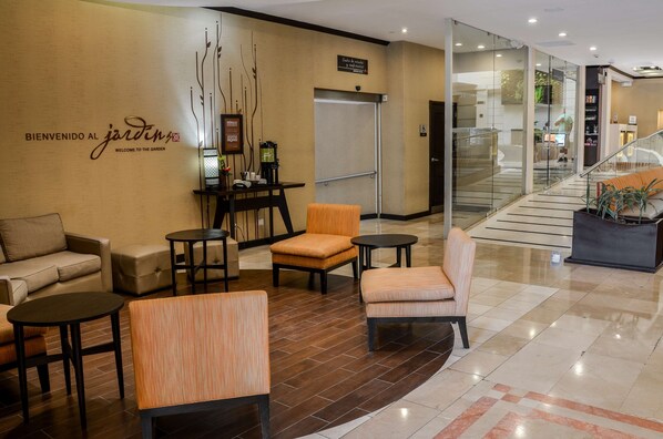 A lobby with a reception desk, seating area, and a staircase. - Hilton Garden Inn Guatemala City (Guatemala City)