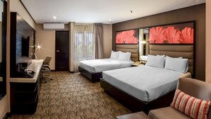 A hotel room with two beds, a desk with a chair, a sofa, and a large floral artwork on the wall. - Hilton Garden Inn Guatemala City (Guatemala City)