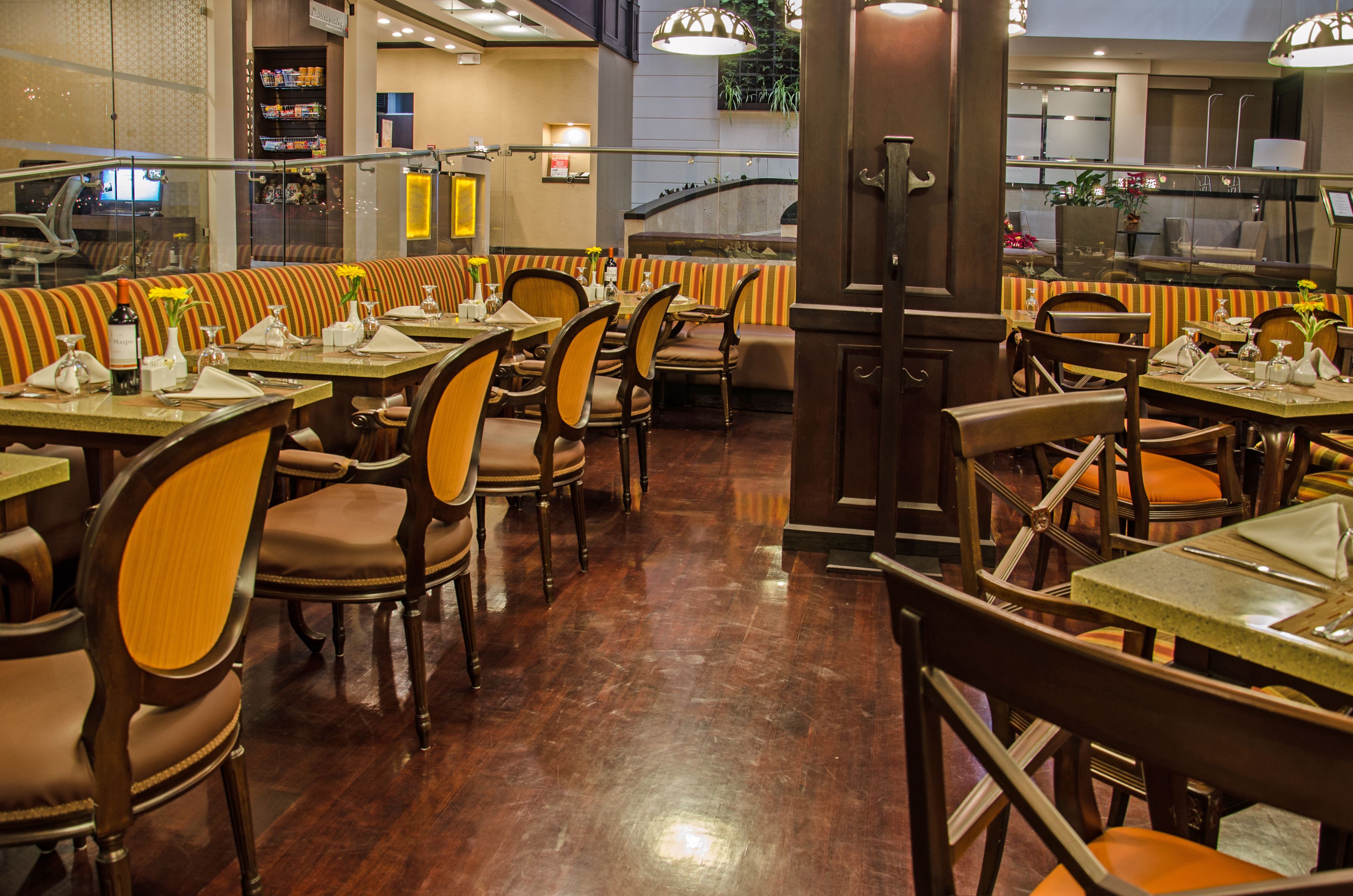 Un restaurante con cabinas y mesas, sillas de madera y piso pulido.