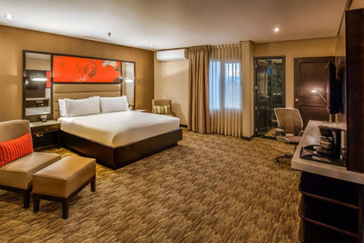 Een hotelkamer met een groot bed, een bureau, een stoel, een televisie en een spiegel.