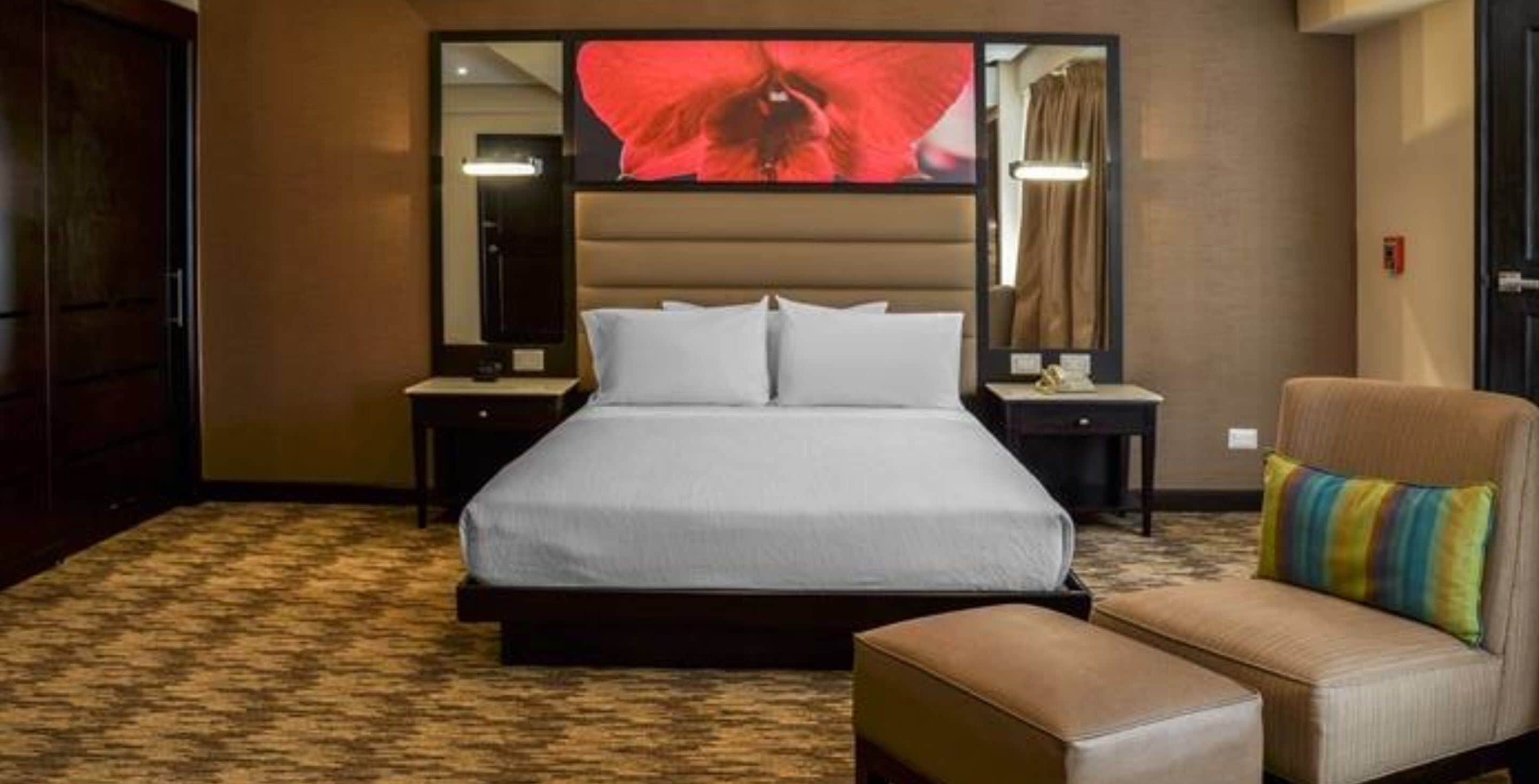 A hotel room with a large bed, two bedside tables, a chair, and a large mirror.