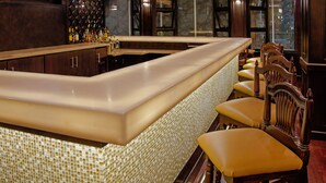 A bar area with a counter, stools, and a decorative wall. - Hilton Garden Inn Guatemala City (Guatemala City)