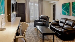 A modern living room with a sofa, armchair, and a desk with a lamp. - Hilton Garden Inn Guatemala City (Guatemala City)