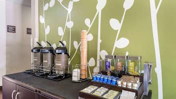 Una estación de desayuno con cafeteras, dispensadores de té y una variedad de alimentos.