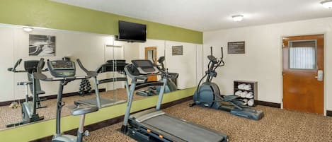 A gym with treadmills, elliptical machines, and a mirrored wall.