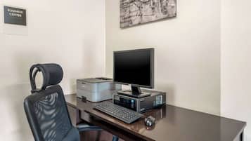 Escritorio de centro de negocios con computadora, impresora y silla.