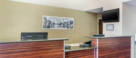 Una recepción con encimera de madera, un televisor de pantalla plana montado en la pared y un certificado enmarcado.