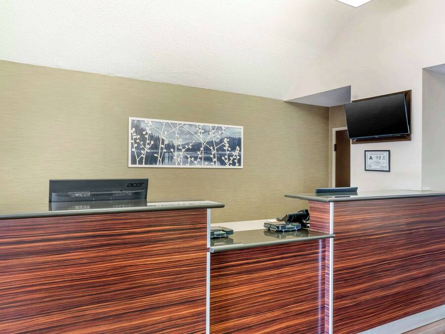 Una recepción con encimera de madera, un televisor de pantalla plana montado en la pared y un certificado enmarcado.