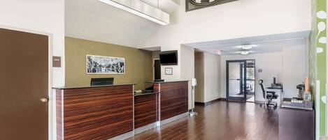 A reception area with a wooden reception desk, a framed picture on the wall, and a modern light fixture above.