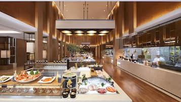 A spacious hotel lobby with a central buffet area featuring seafood and various dishes.