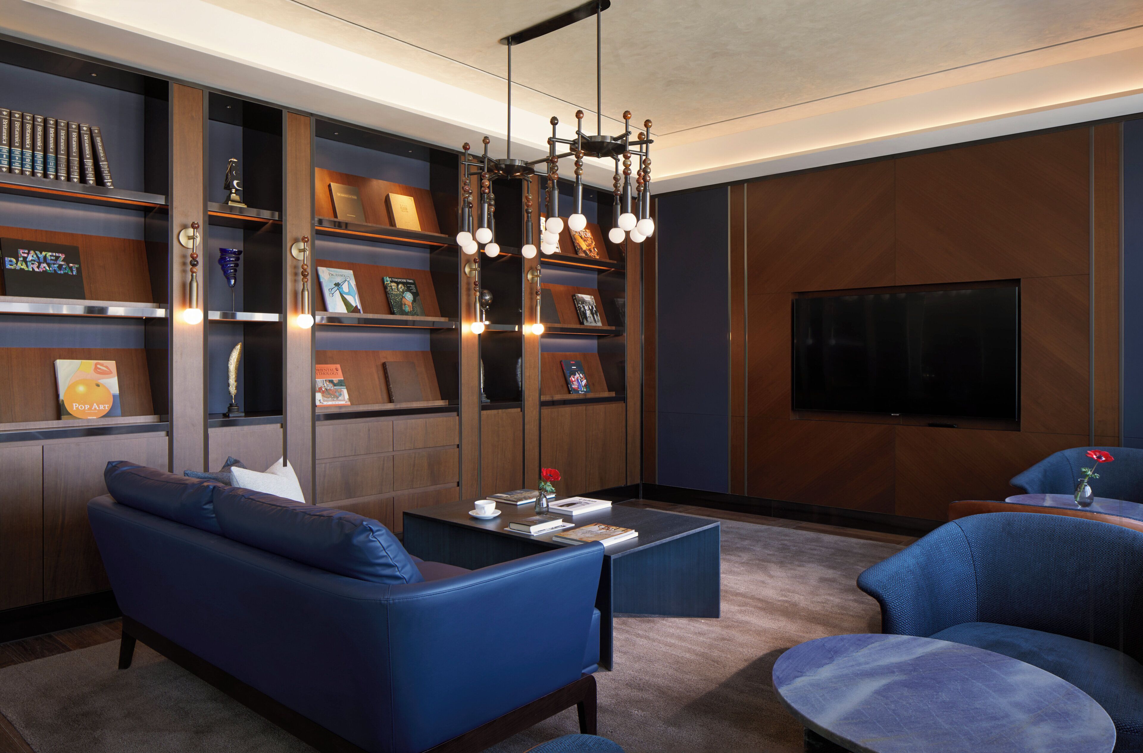 A modern living room with a blue sofa, a coffee table, and a bookshelf.