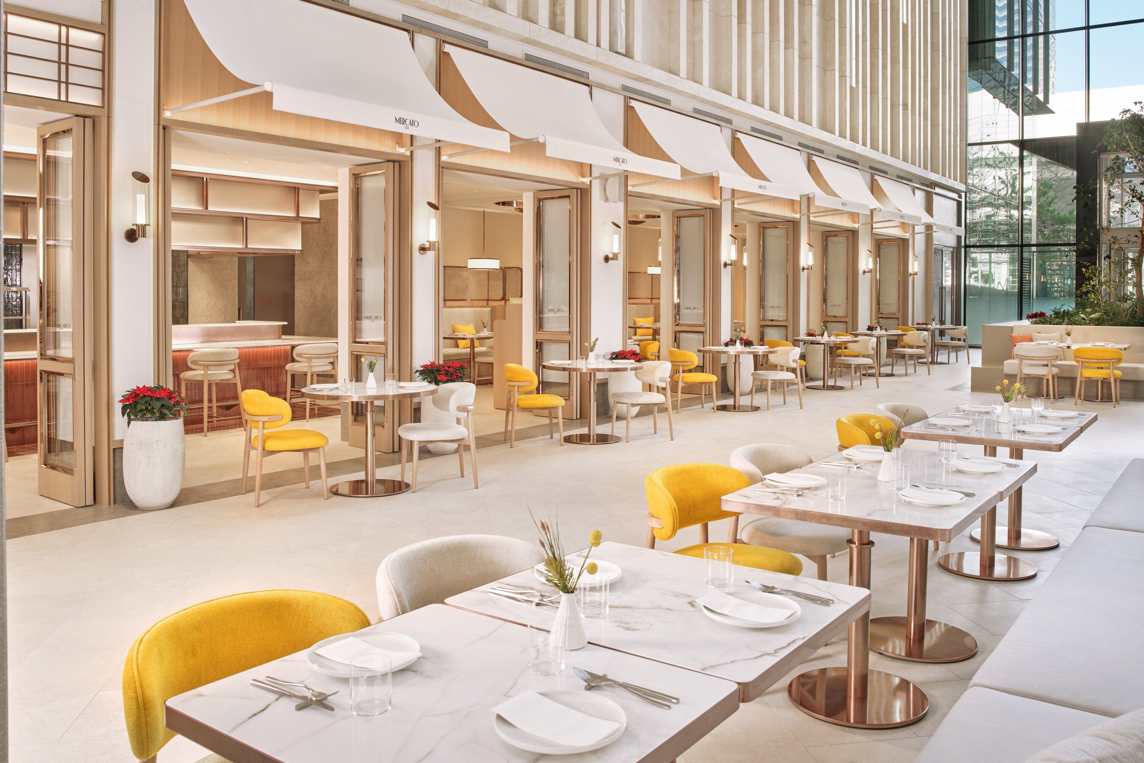 Un restaurante moderno con varias mesas, sillas amarillas y un amplio ventanal.