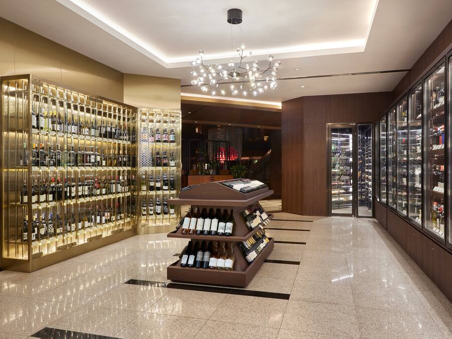 A luxurious wine cellar with glass-fronted shelves displaying various bottles.