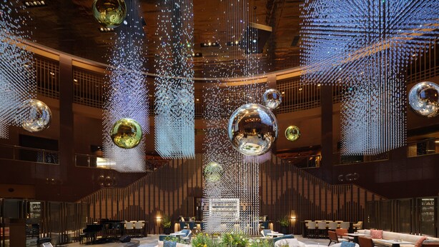Un vestíbulo amplio con muebles modernos, iluminación decorativa y un arreglo floral central.