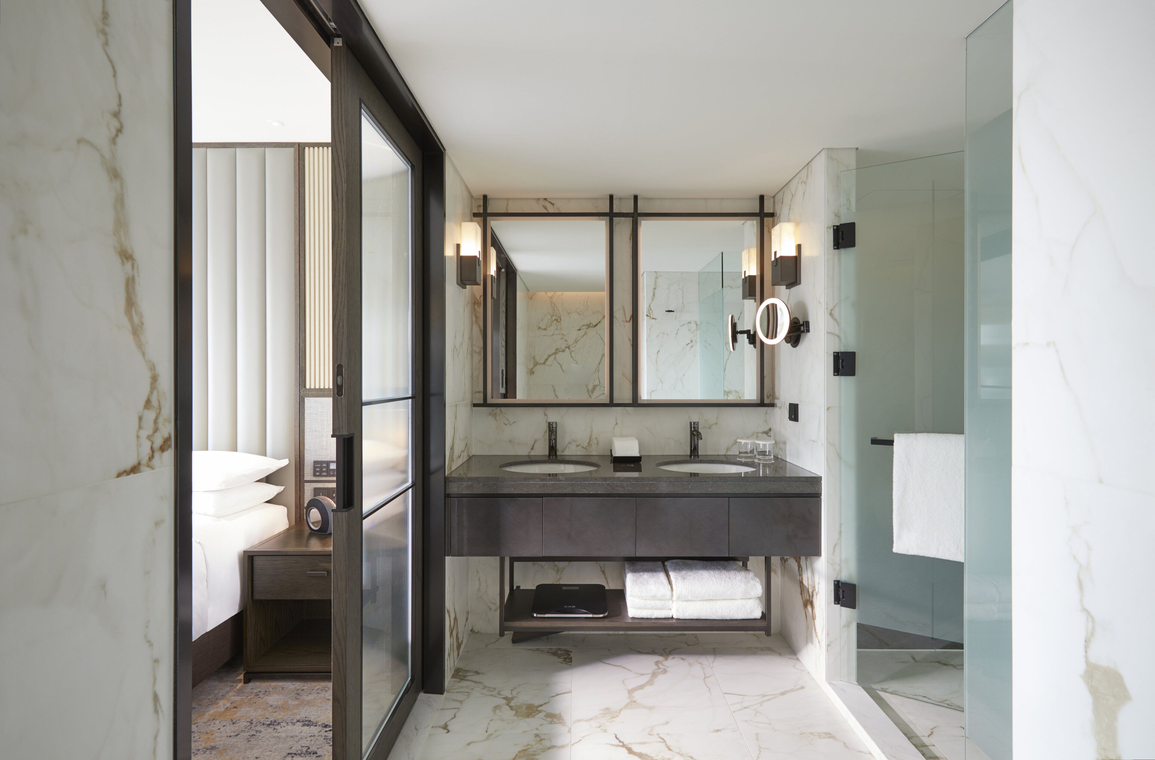 Un baño moderno con dos lavamanos, un espejo grande y una cabina de ducha de vidrio.